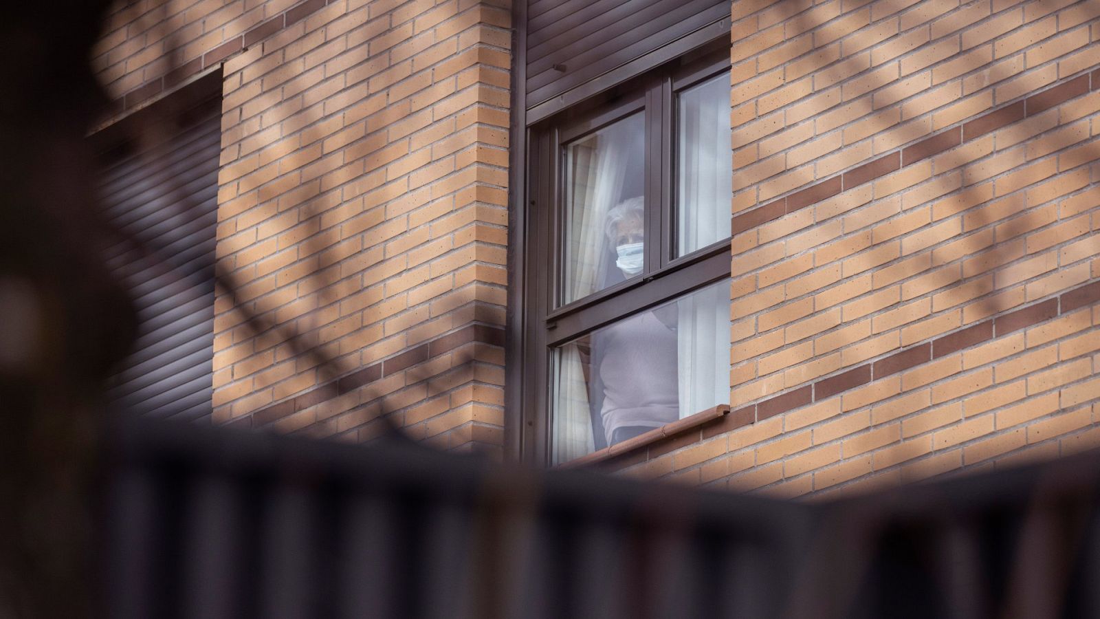 Una mujer observa desde el interior de la residencia para mayores