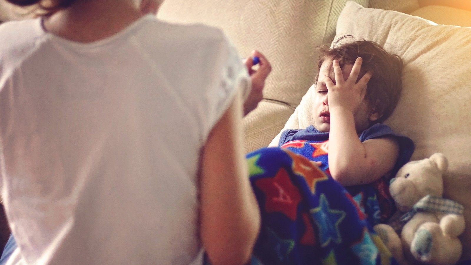 Un niño enfermo descansa en un sofá junto a su madre, en una imagen de archivo