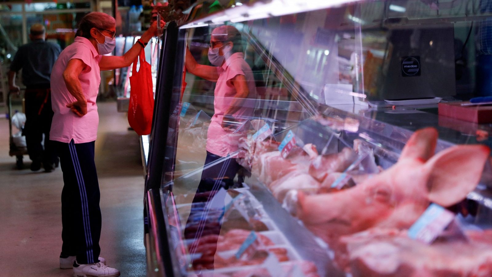 Una mujer compra en una carnicería de un mercado