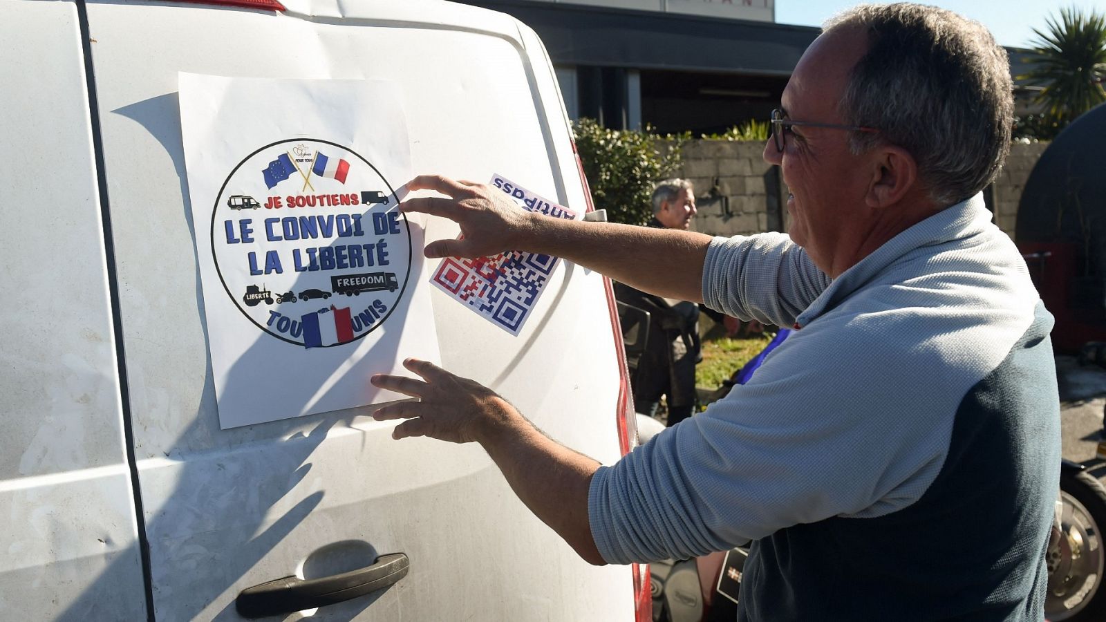 Una persona pega un cartel del 'Convoy de la libertad' en su vehículo