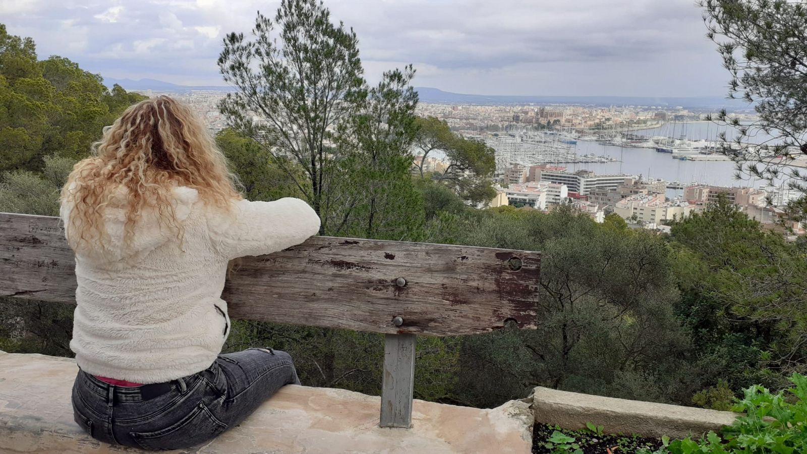 Un chica de pelo largo y rizado, sentada, mira hacia Palma de Mallorca