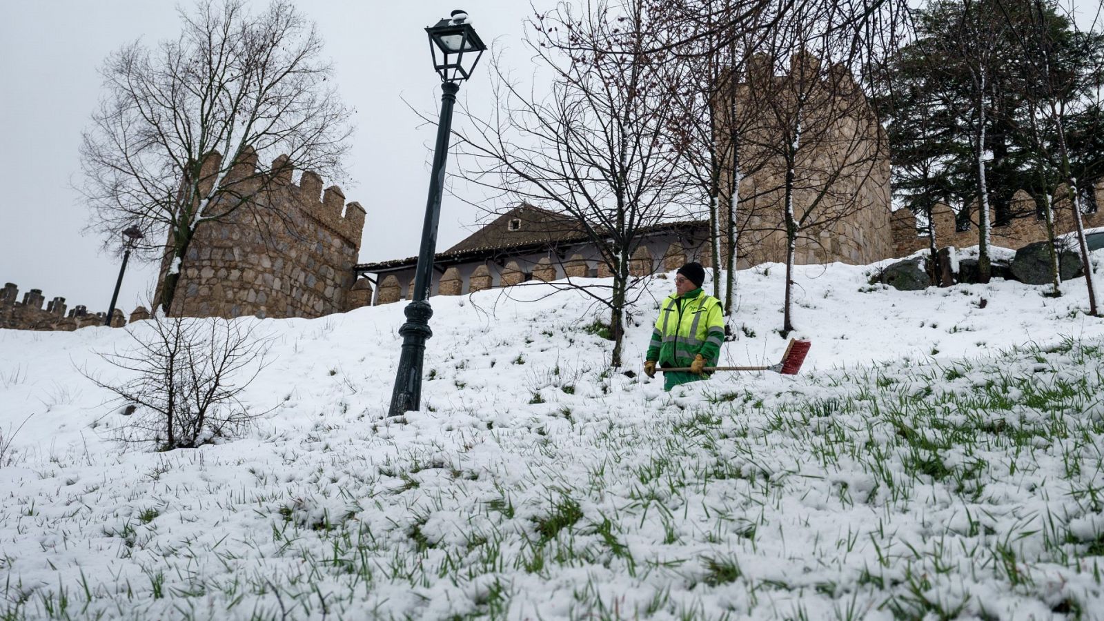 Un operario retira la nieve caída durante la noche junto a la muralla de Ávila, este viernes