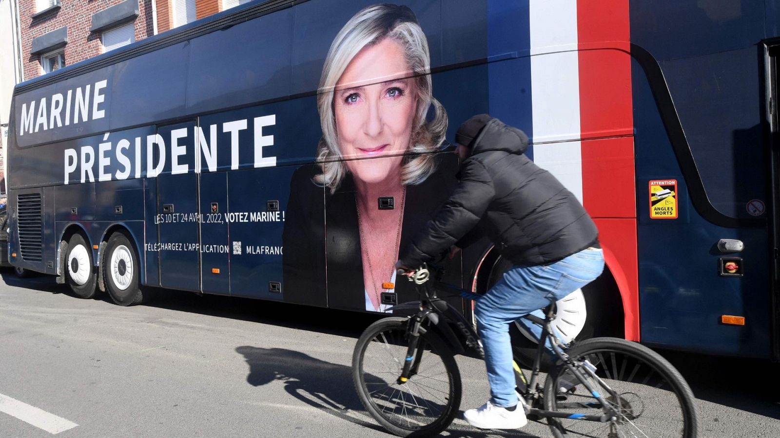 Un ciclista pasa delante de un autobús de campaña de la aspirante ultraderechista a la Presidencia francesa Marine Le Pen.