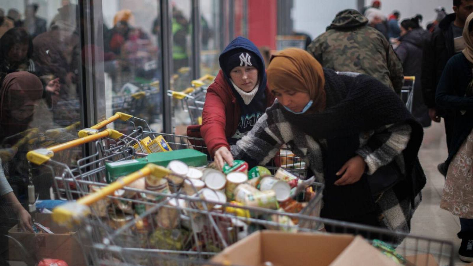 Varias personas cogen alimentos en un centro comercial de Korczowa habilitado para alojar a ciudadanos procedentes de Ucrania que han huído de la guerra.