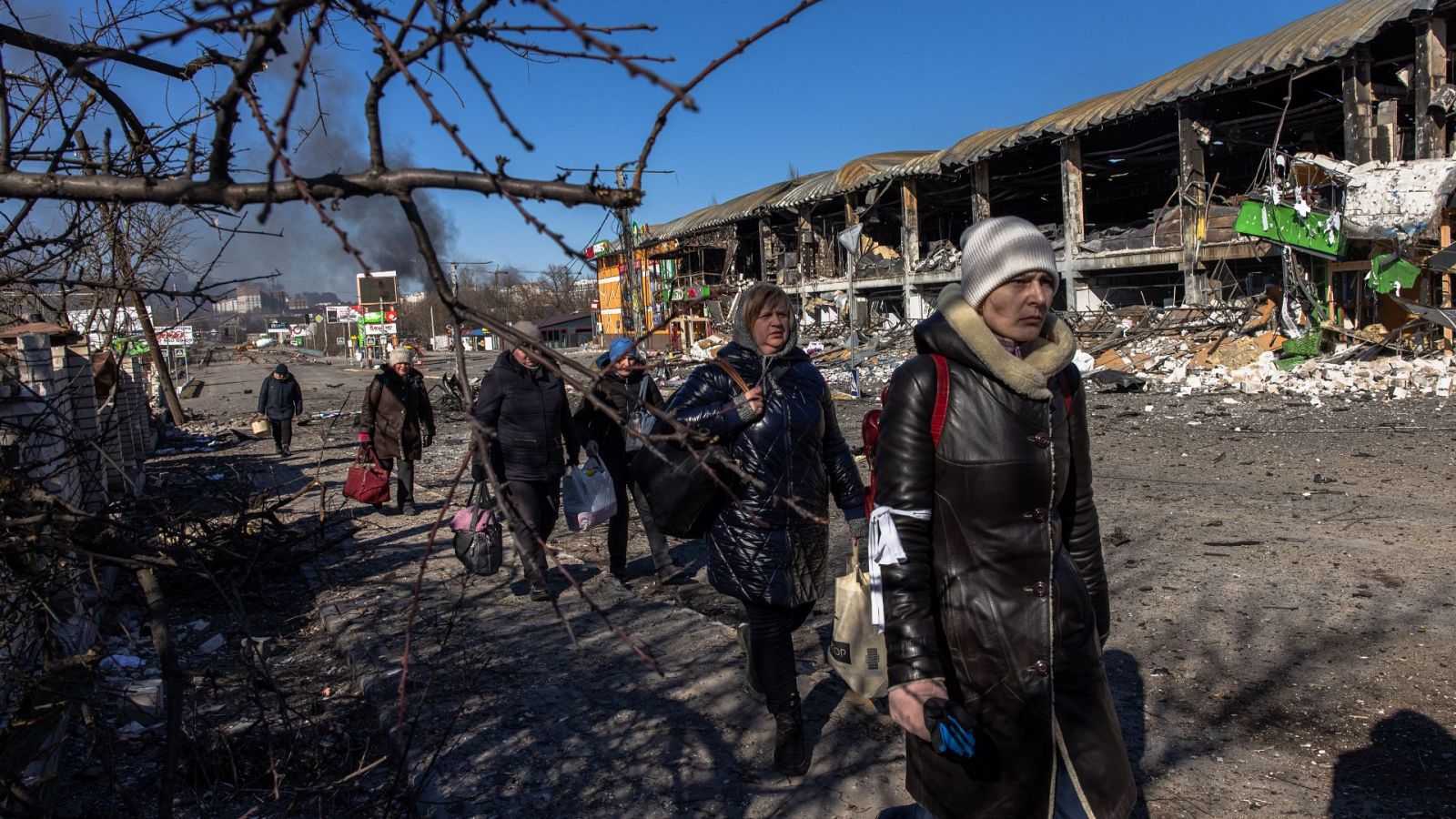 Varias personas caminan con maletas en una zona de Ucrania afectada por la guerra
