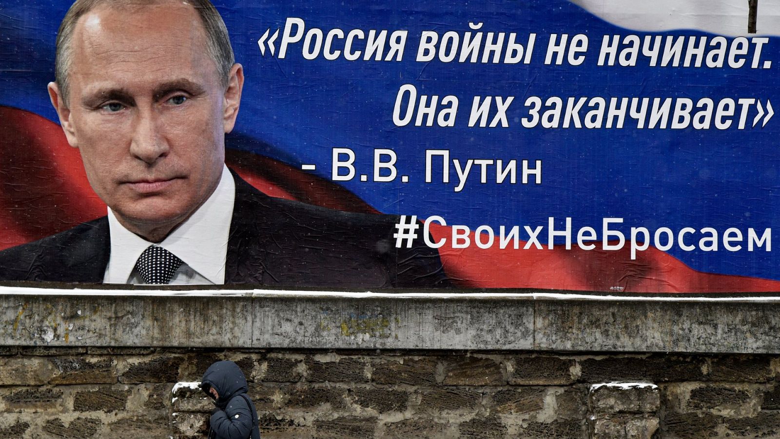 Un hombre pasa junto a dos carteles con una foto del presidente ruso Vladimir Putin con el lema; 'Rusia no inicia guerras, las termina' en una calle de Simferopol, Crimea