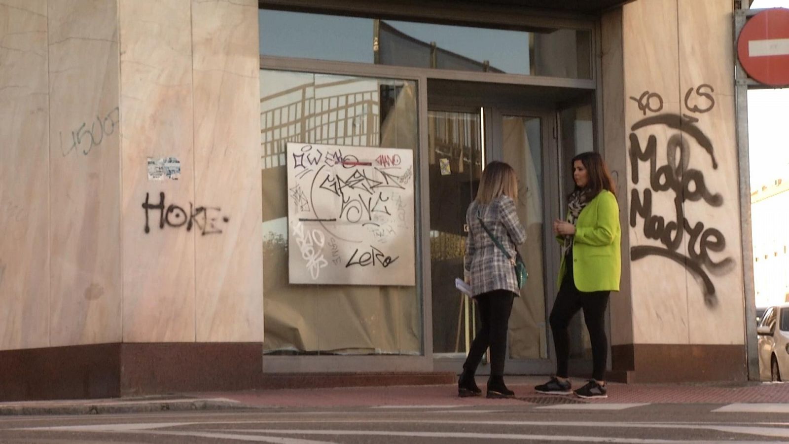 Una reportera de Comando Actualidad conversa con una antigua empleada frente a una sucursal bancaria cerrada.