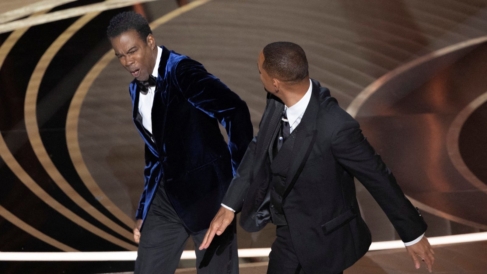 El actor Will Smith (dcha.) abofetea al humorista Chris Rock en la gala de los Premios Oscar 2022