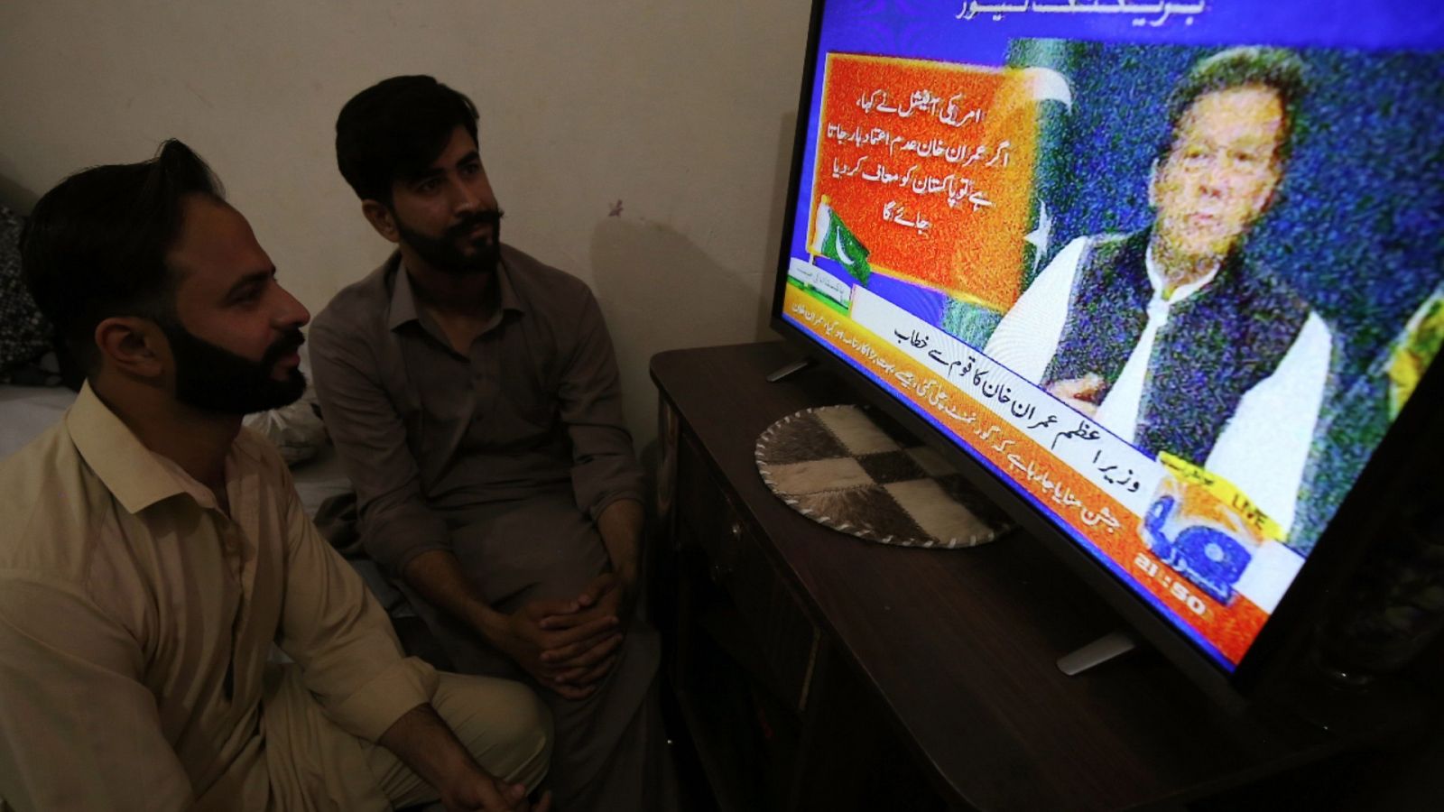 Imagen de archivo de dos hombres viendo en una televisión un discurso del primer ministro de Pakistán, Imran Khan.