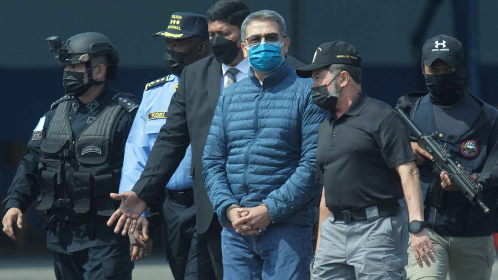 El expresidente de Honduras Juan Orlando Hernández (con mascarilla azul) en la Base Aérea Hernán Acosta Mejía antes de subirse al avión para ser extraditado a Estados Unidos.