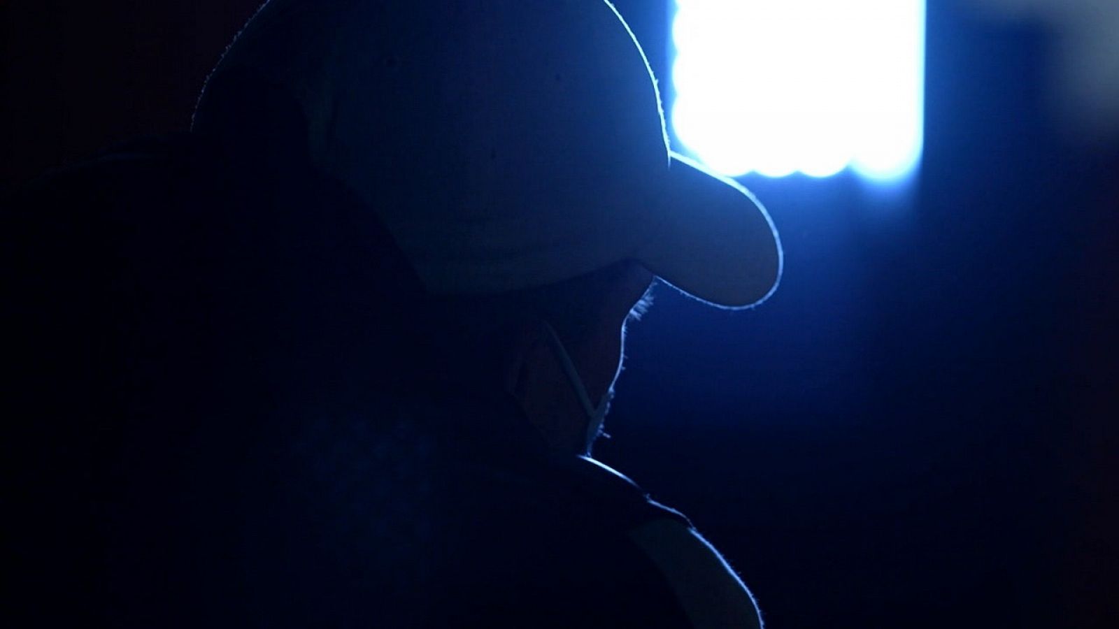 Imagen de perfil del traficante con gorra, mascarilla y luz en contra para no ser reconocido.