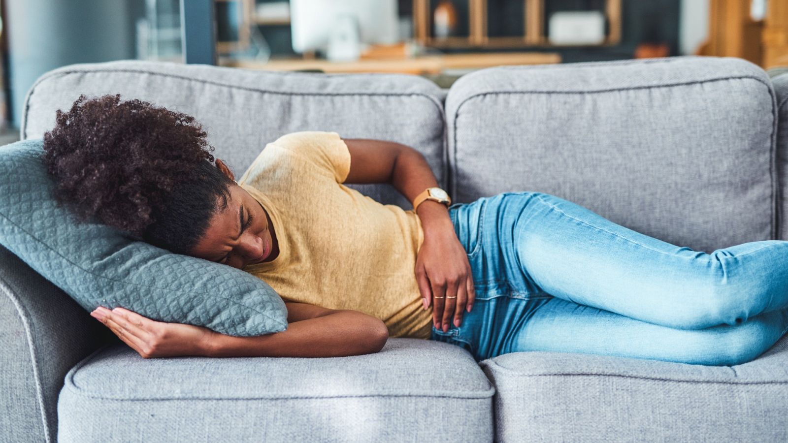 Una mujer sufre dolores menstruales, tumbada en un sofá, en una imagen de archivo