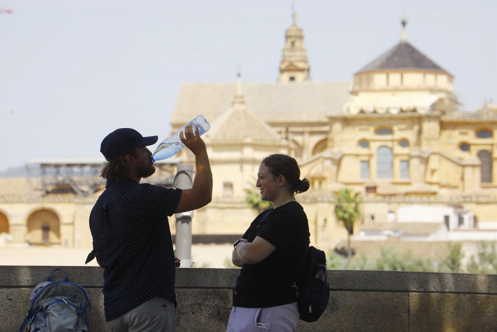 Dos turistas descansan y beben agua frente a la Mezquita-Catedral de Córdoba