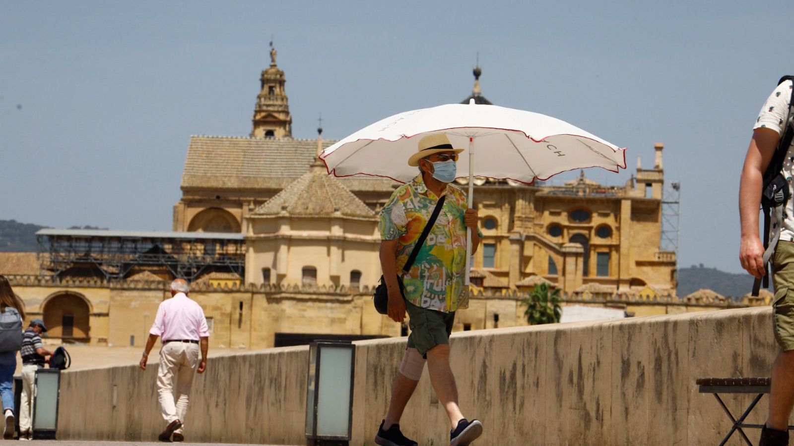 Una persona se protege con una sombrilla del intenso calor en el puente romano de Córdoba