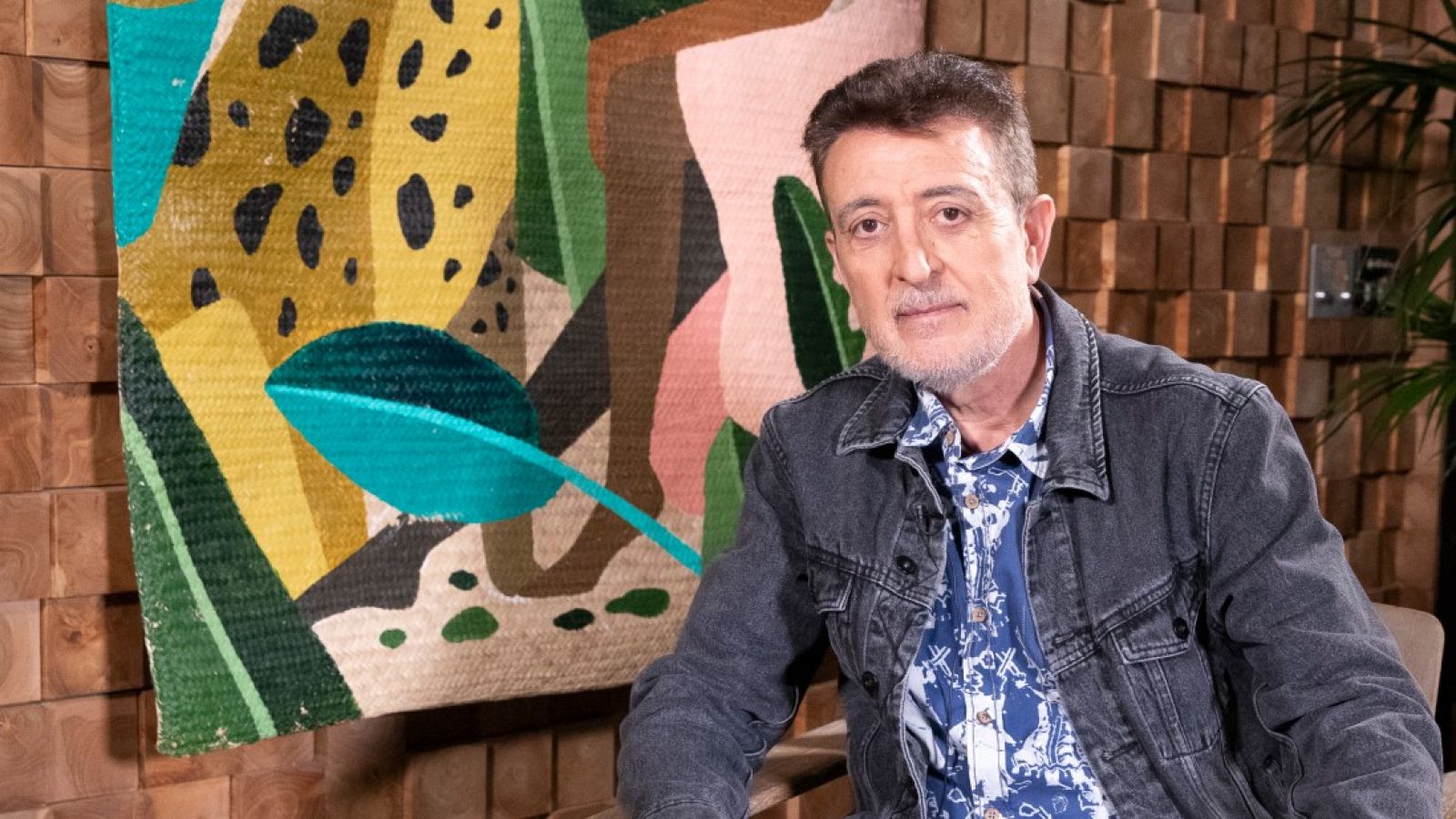 Manolo García posa con un colorido cuadro detrás.