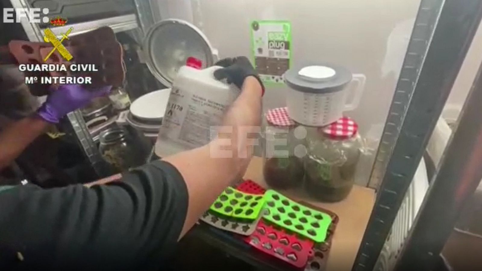 Un agente de la Guardia Civil muestra los elementos incautados en el laboratorio que producía gominolas con marihuana.