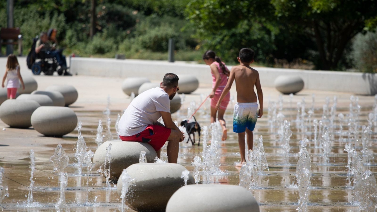 Diversas personas se refrescan con unos surtidores en un parque en el barrio de Sant Andreu (Barcelona)