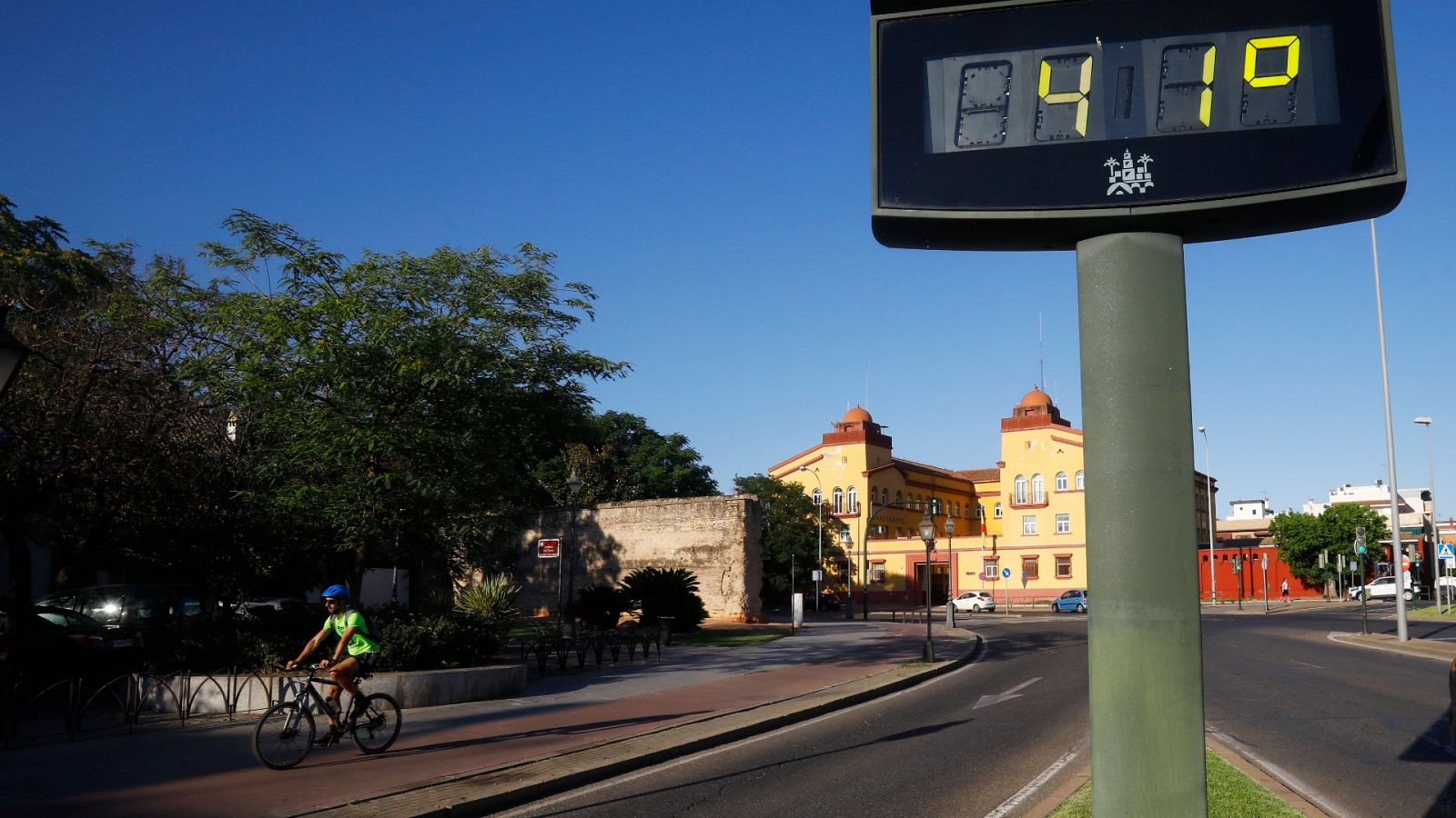 Un ciclista pasa junto a un termómetro que marca 41 grados en Córdoba