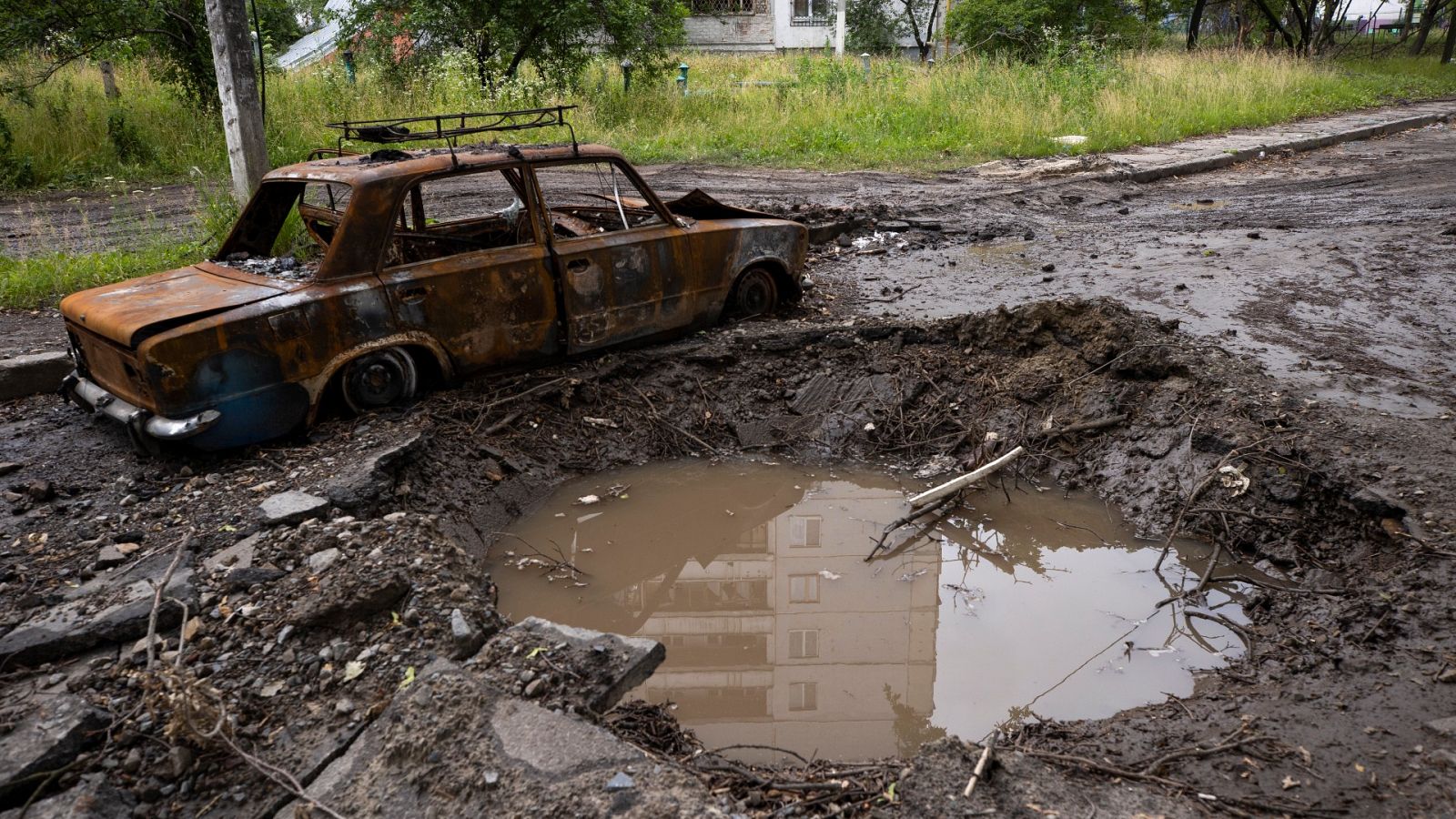 Un automóvil destruido junto al cráter dejado por una explosión en Járkov
