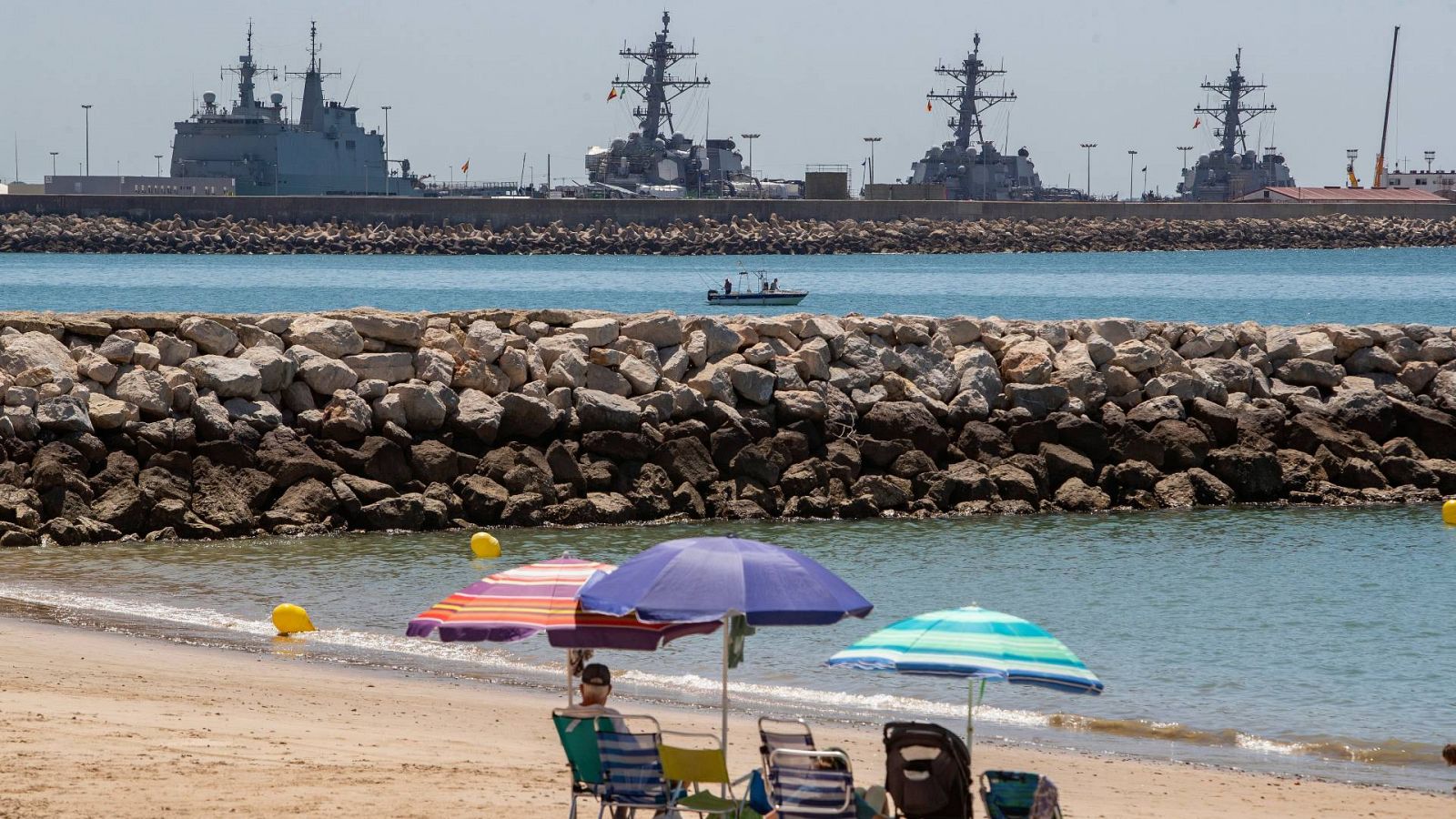 Una playa de Rota, con los buques estacionados en la base naval al fondo