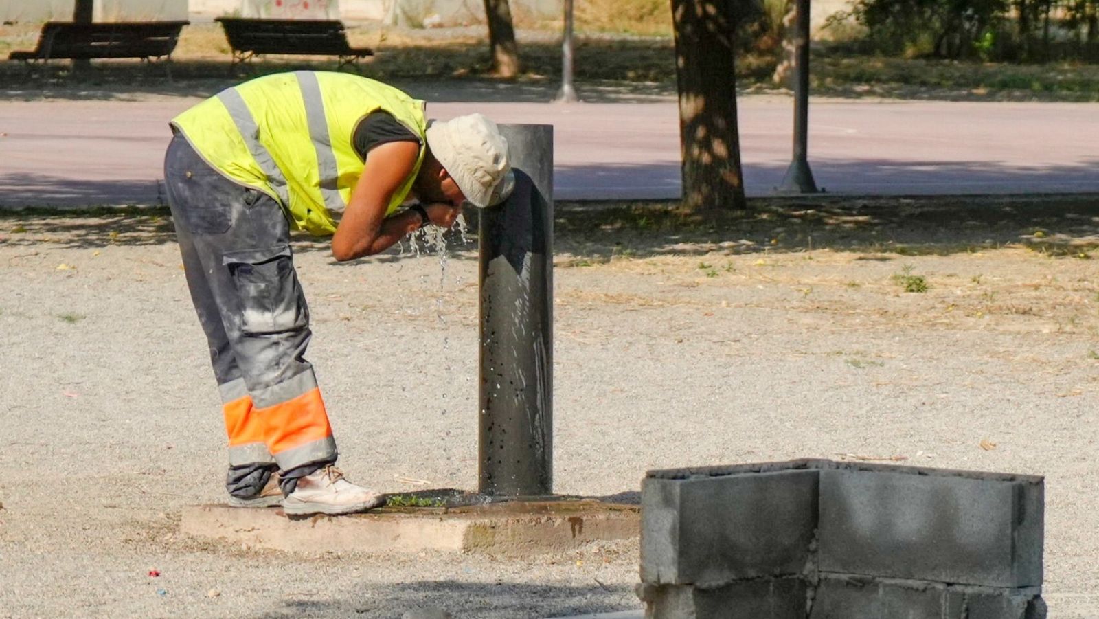 Un trabajador se refresca en un fuente de un parque de Lleida, este viernes