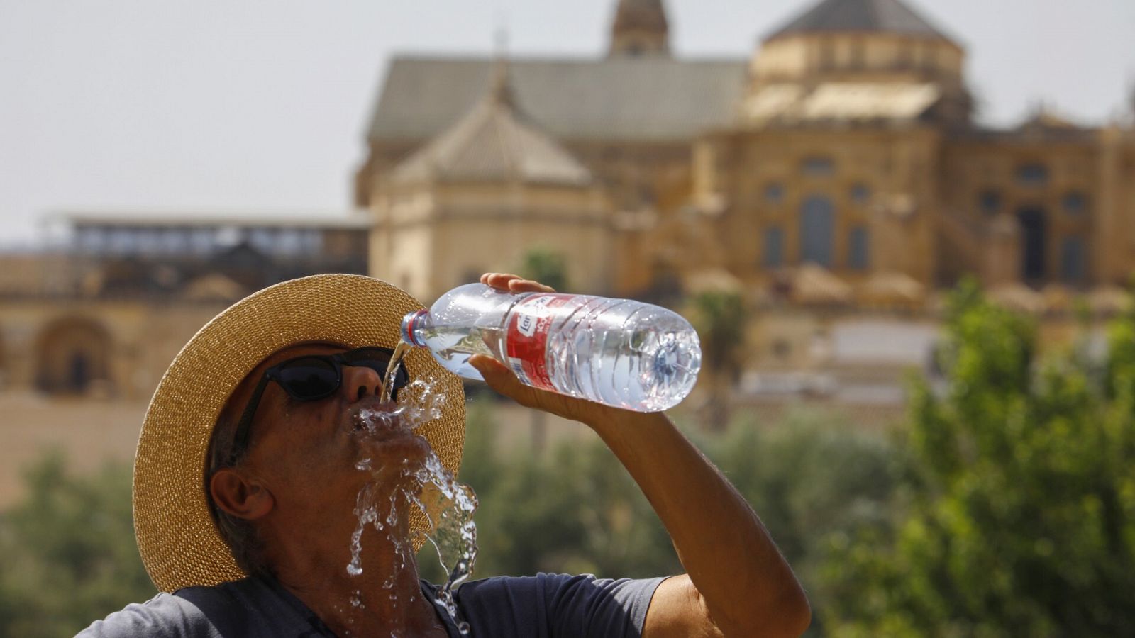 Un turista bebe agua ante la Mezquita-Catedral de Córdoba