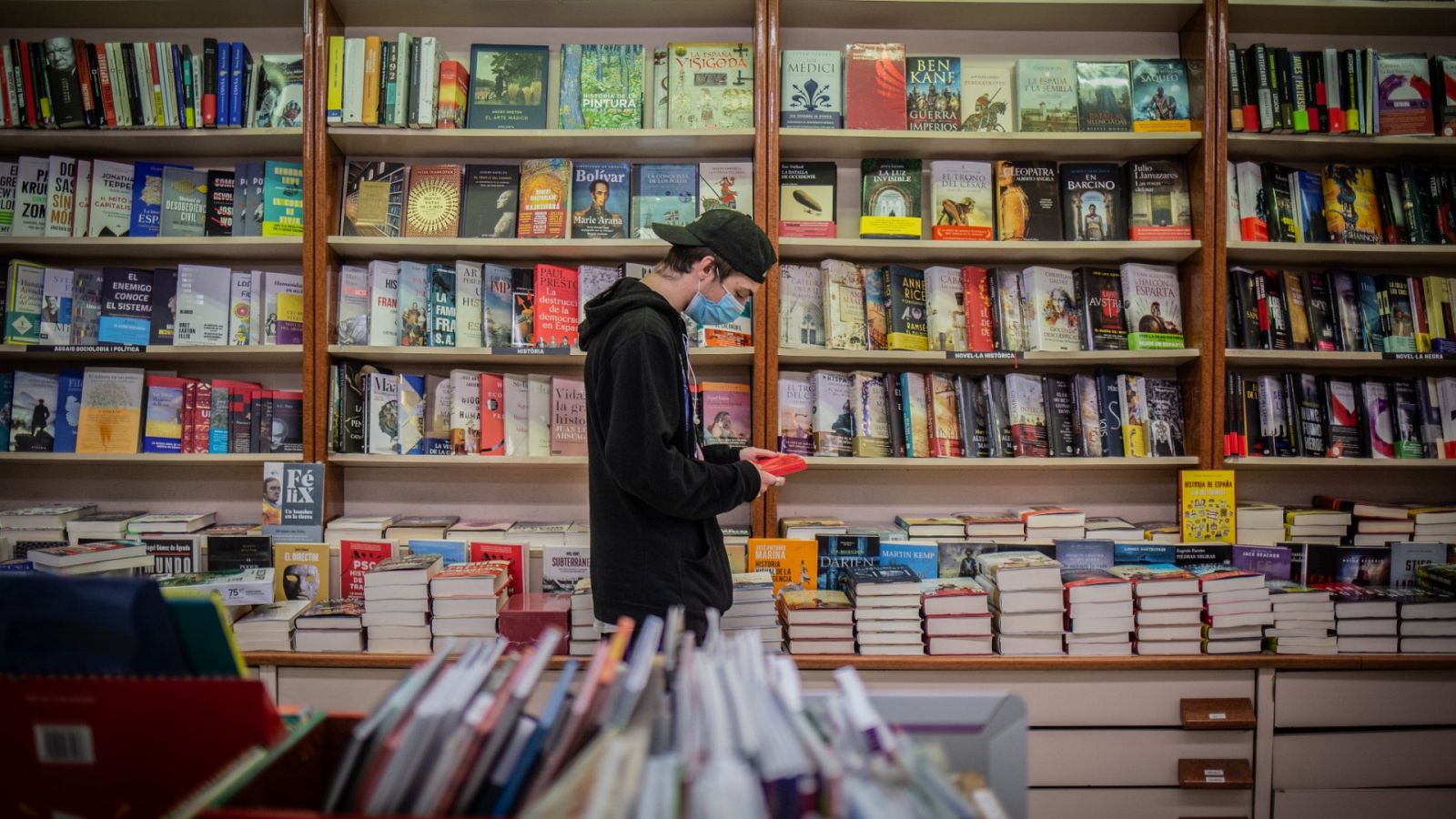 Un joven observa un libro en una librería durante la pandemia de coronavirus.