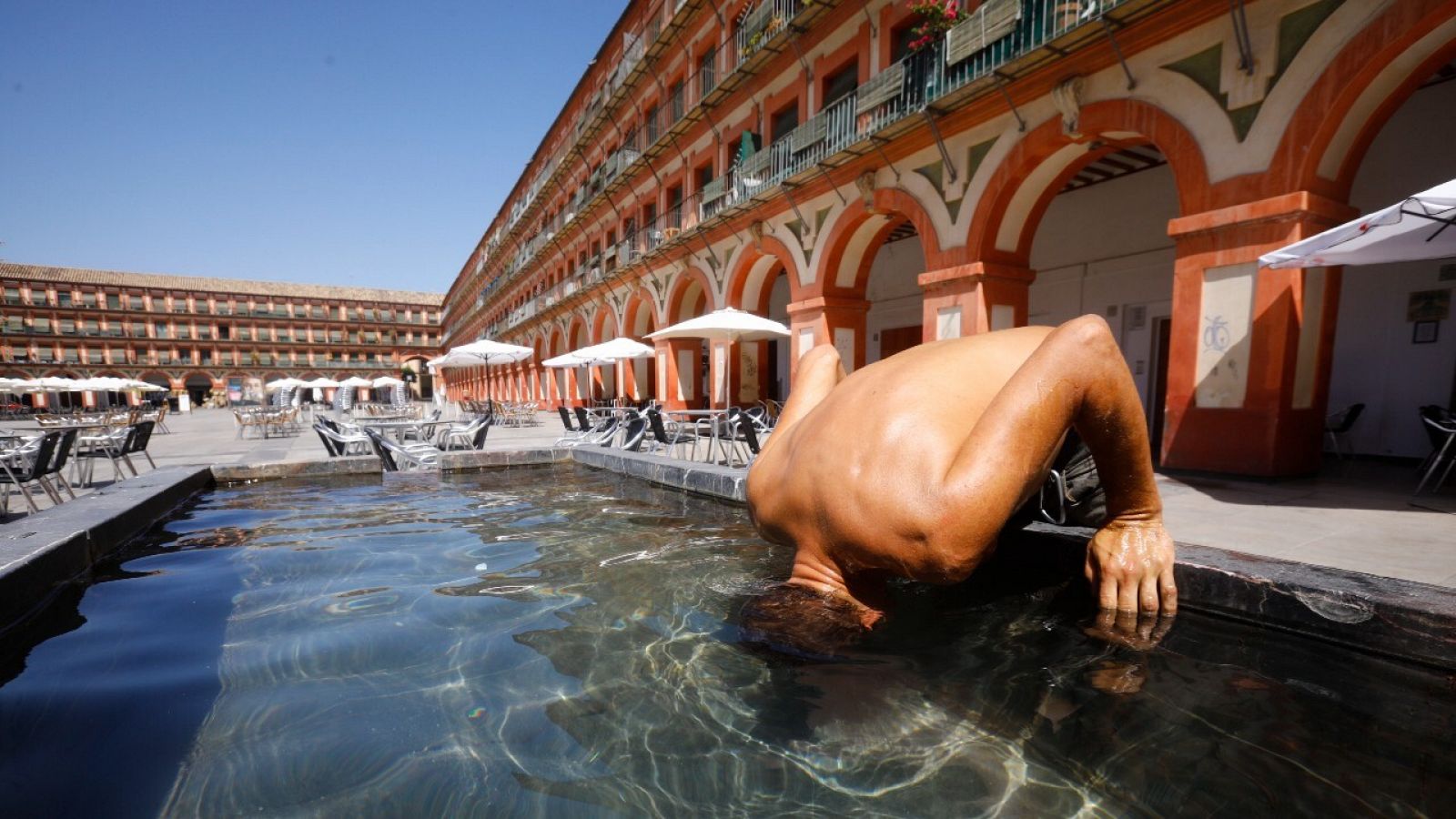 Un hombre mete la cabeza en la fuente de la plaza de la corredera de Córdoba