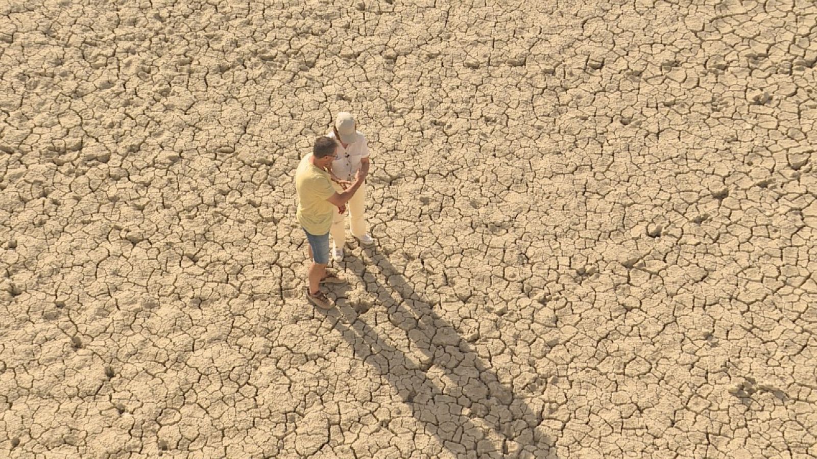 Plano cenital de dos personas en un terreno completamente agrietado y seco