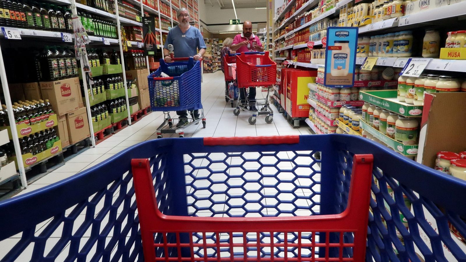 Varias personas empujan un carrito de la compra en un supermercado Carrefour