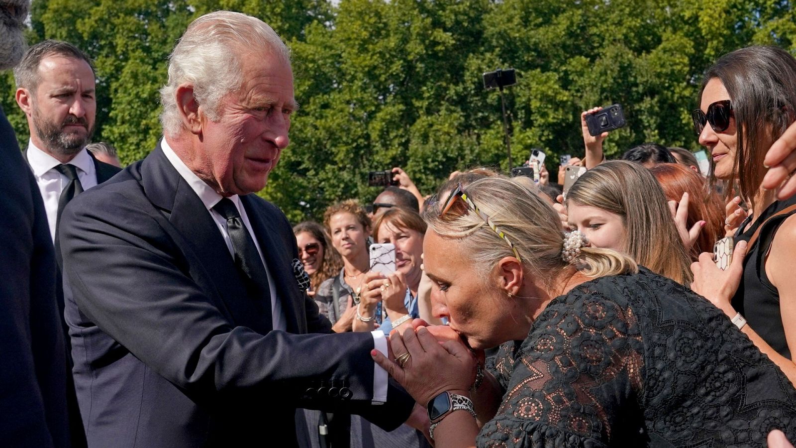 Una mujer besa la mano del rey Carlos III en el Palacio de Buckingham