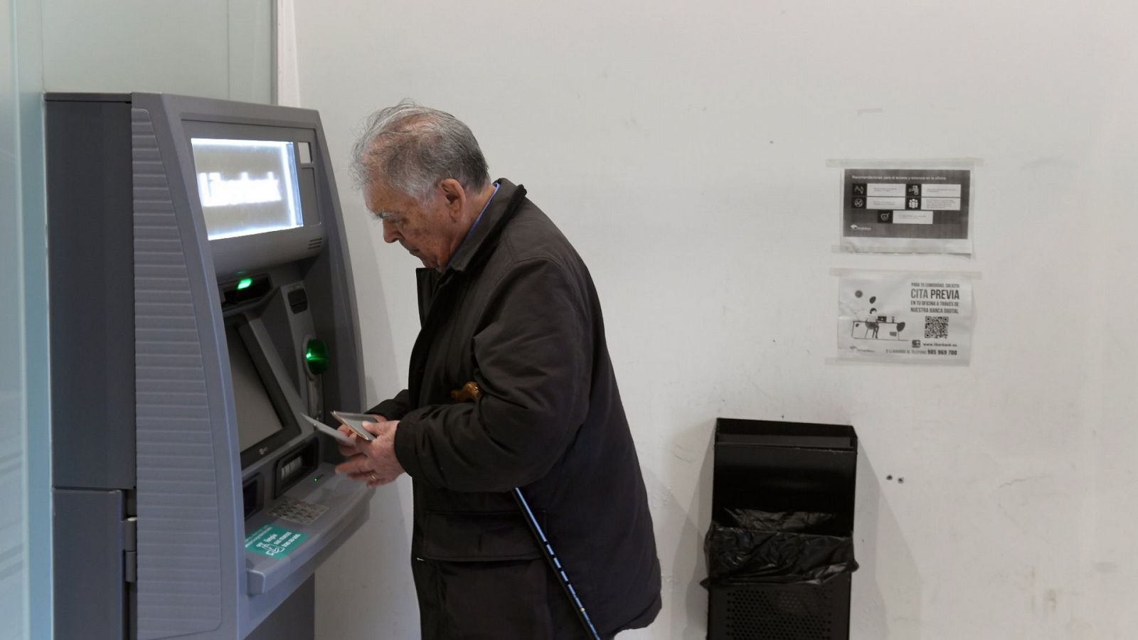Un hombre saca dinero de un cajero automático de una entidad bancaria
