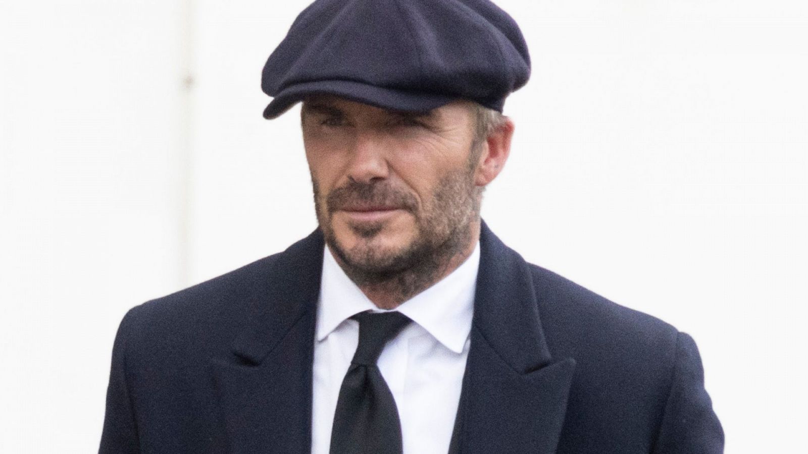 David Beckham co traje, corbata y gorra negra