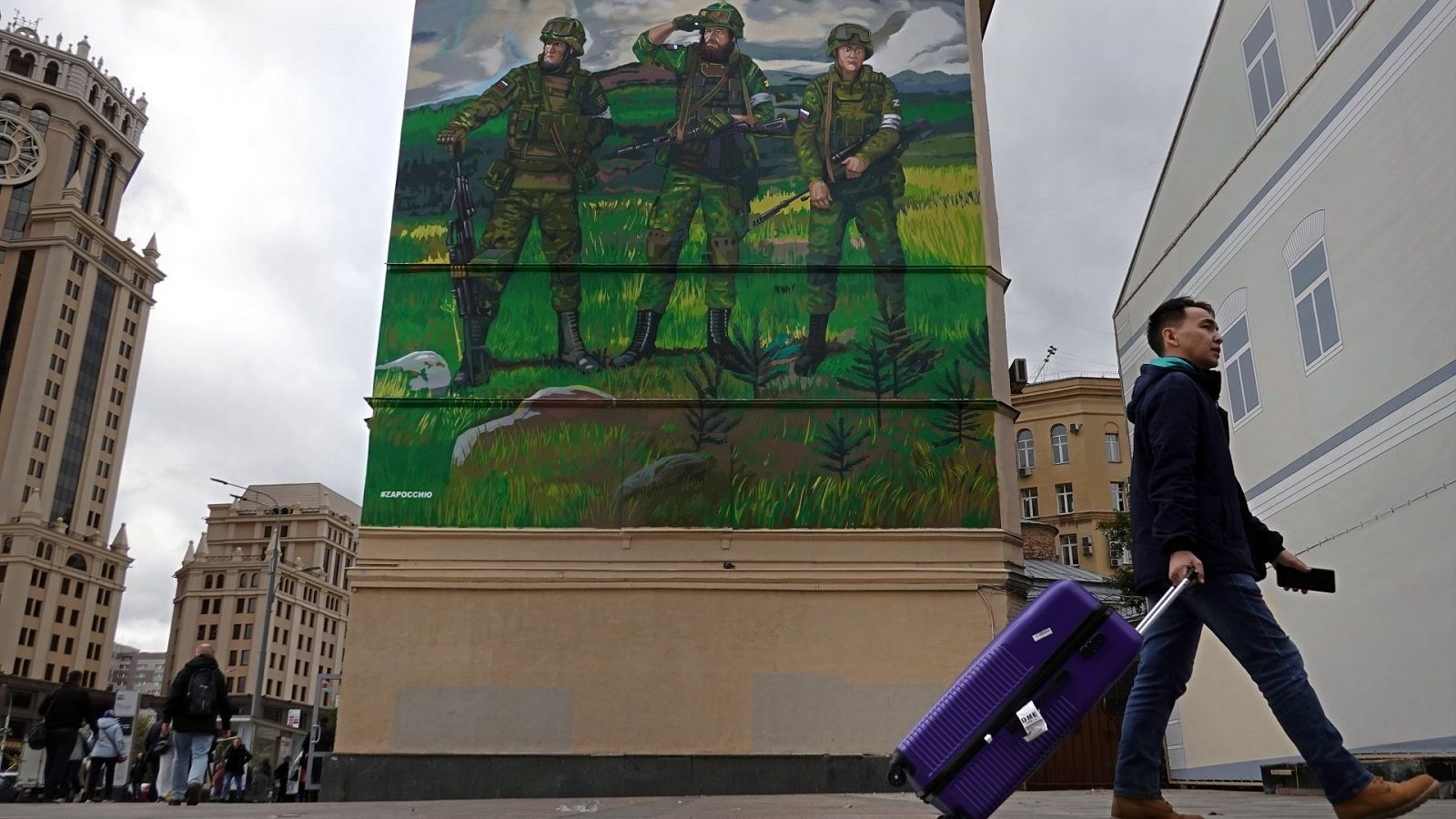 Un hombre pasa ante unos apartamentos con un mural en apoyo de la "operación militar especial" de Rusia en Ucrania