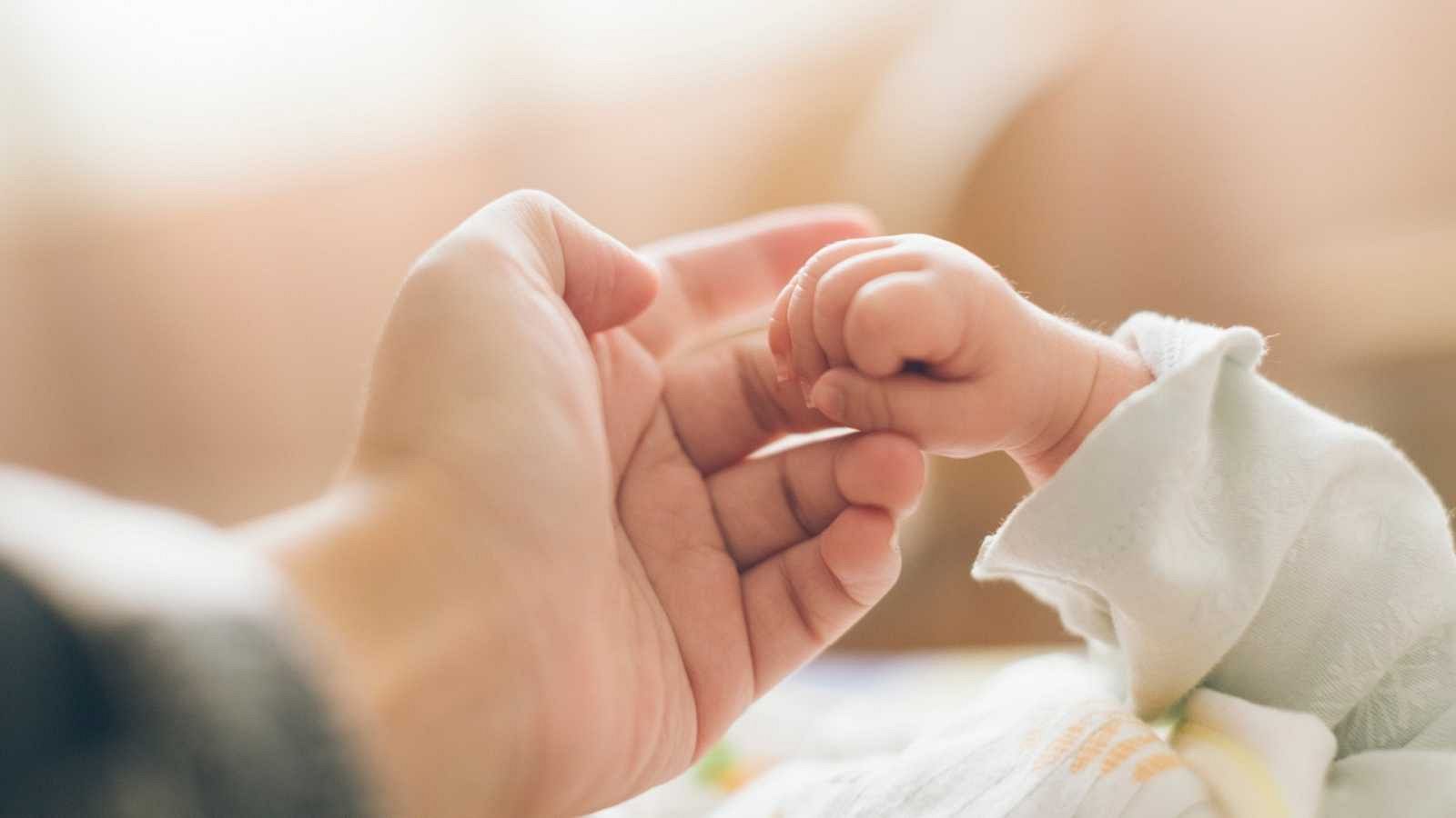 Una madre coge la mano de su bebé recién nacido