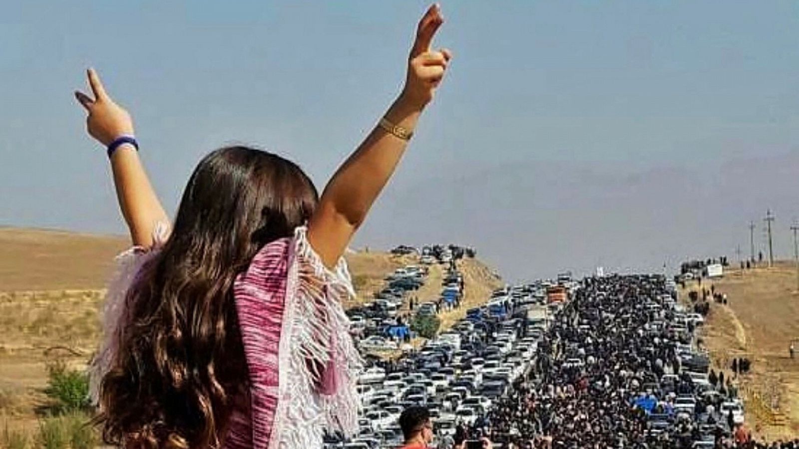 Esta imagen UGC publicada en Twitter muestra a una mujer sin velo de pie sobre un vehículo mientras miles de personas se dirigen hacia el cementerio de Aichi en Saqez (Irán), la ciudad natal de Mahsa Amini.