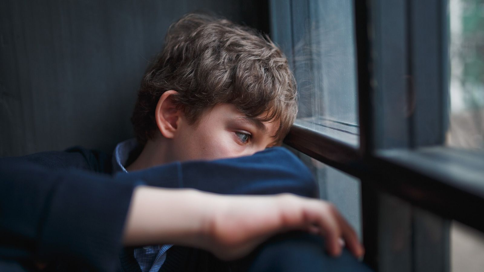 Un niño mira por la ventana en una imagen de archivo