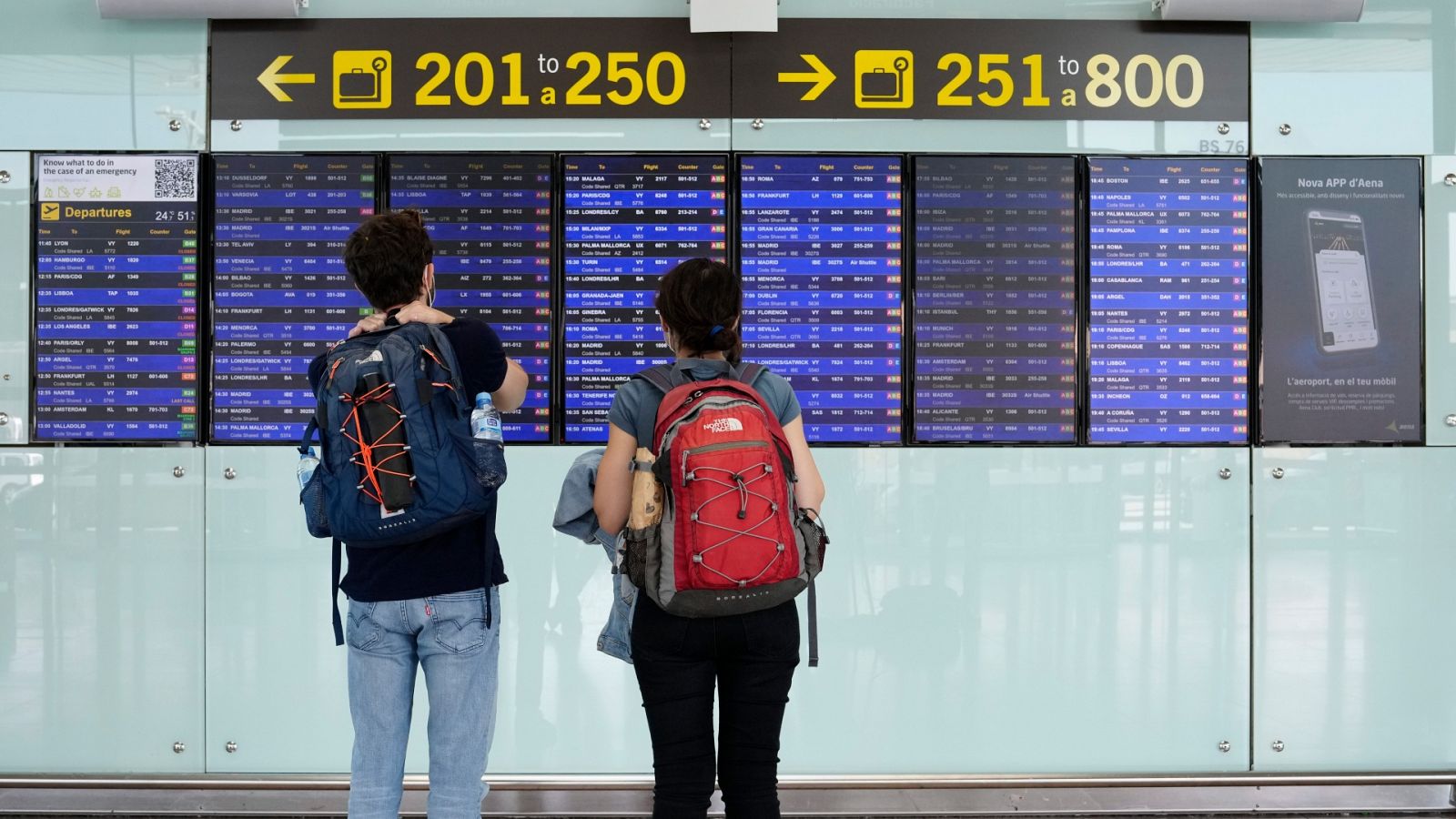 Dos viajeros consultan los paneles con los vuelos programados en el aeropuerto de El Prat, en Barcelona.