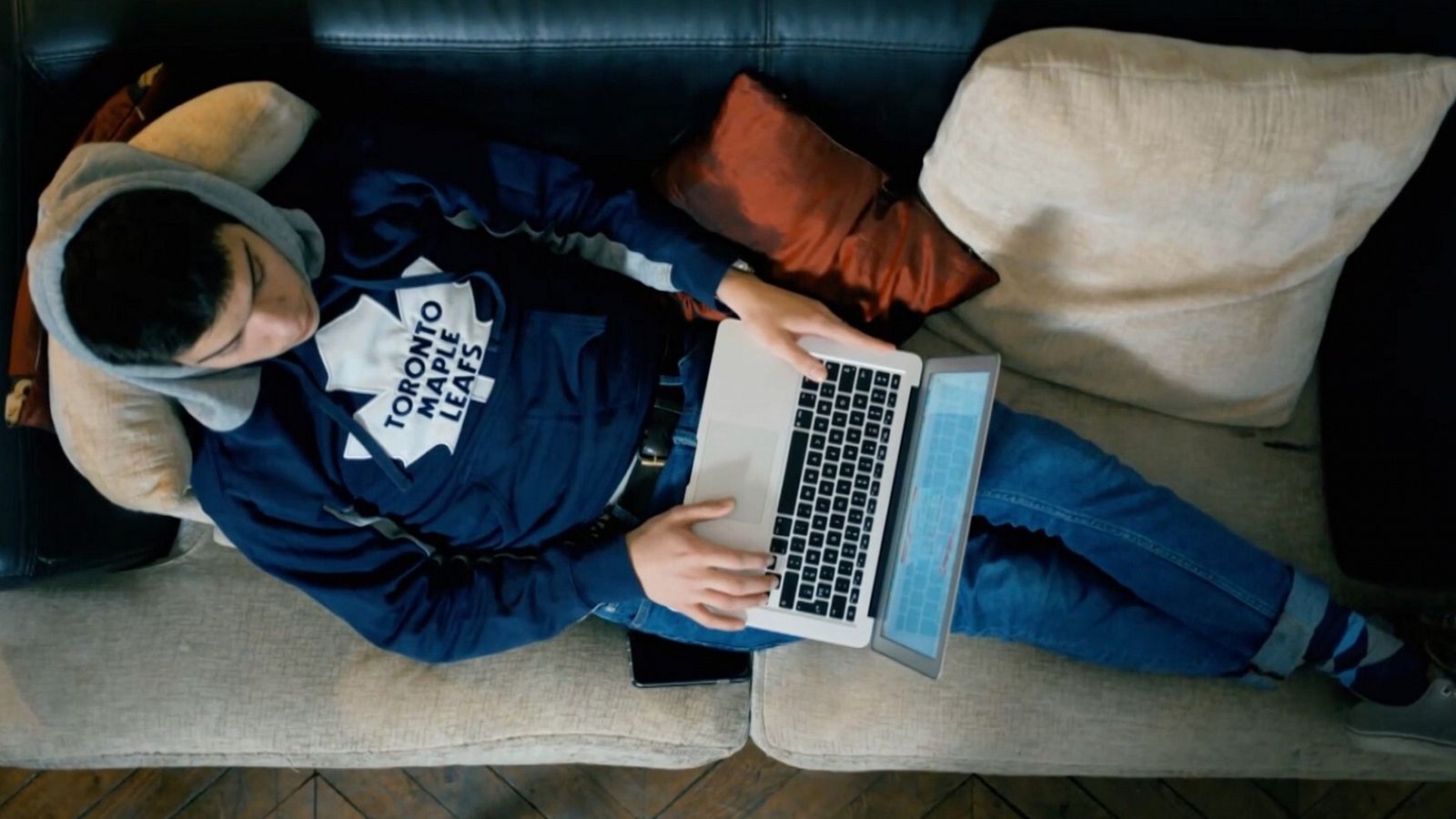 Un joven navega por internet con un portátil.