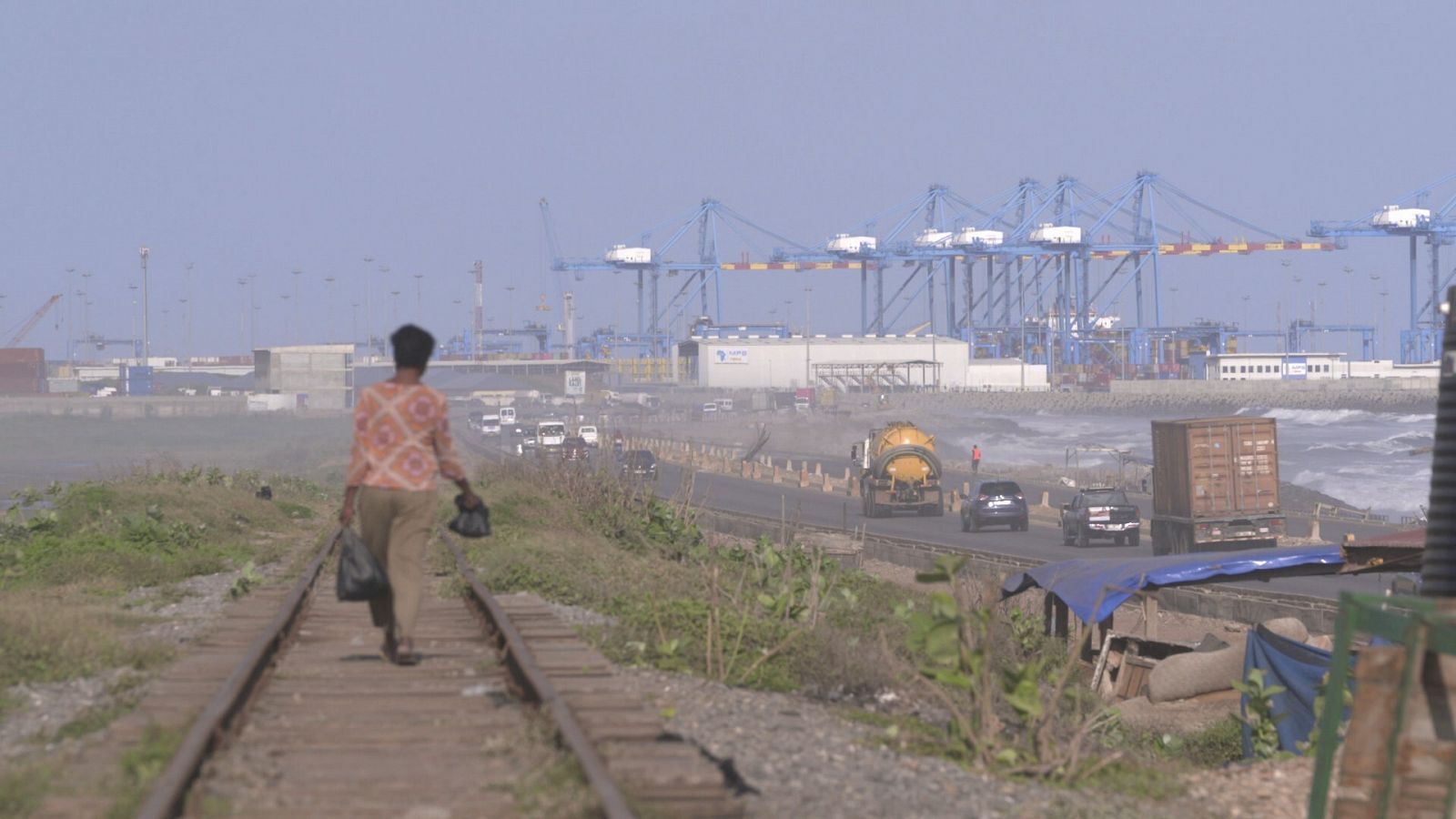 Señora caminando por la via del tren junto a la carretera del puerto en Ghana