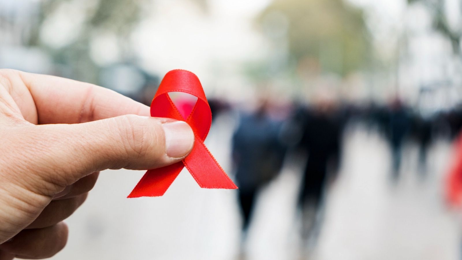 Una mano sostiene un crespón rojo, símbolo de la prevención del VIH