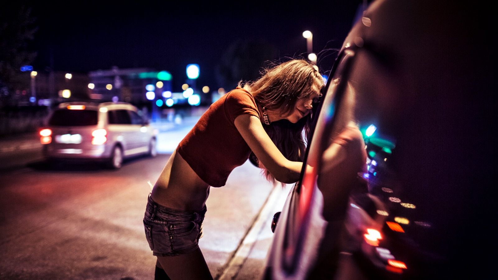 De noche, una joven se asoma al interior de un coche