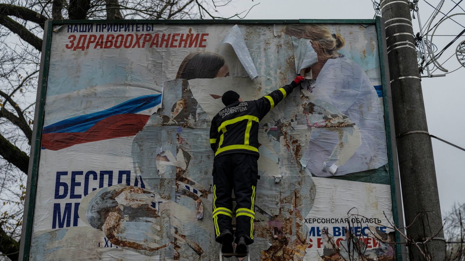 Un operario ucraniano retira carteles rusos en la ciudad de Jersón tras ser recuperada por Kiev.