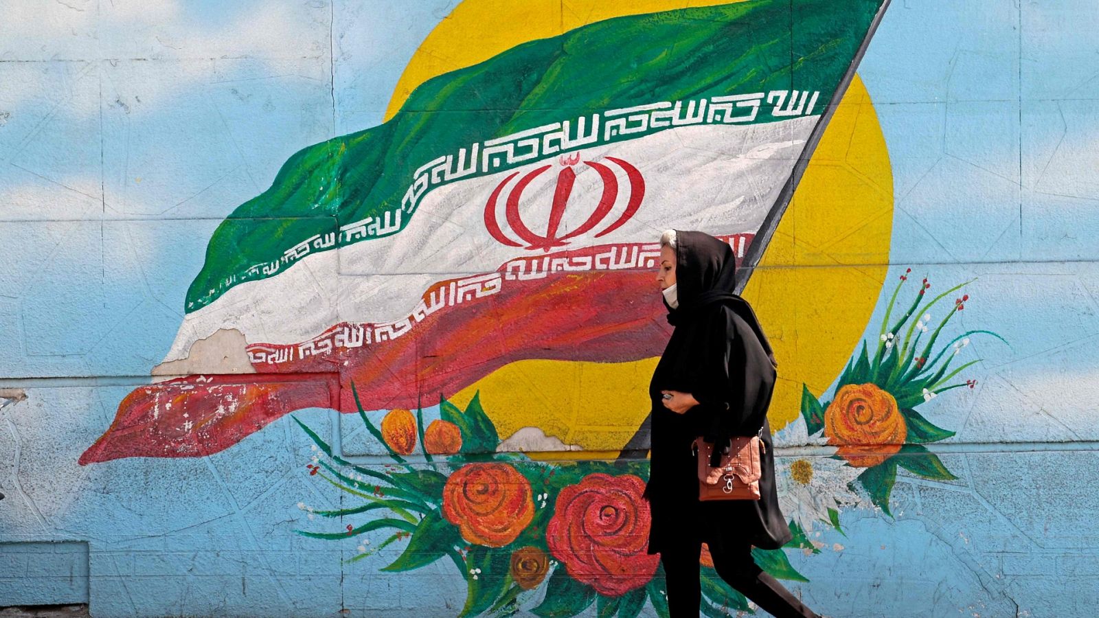 Una mujer pasa por delante de un mural en Teheran, Irán