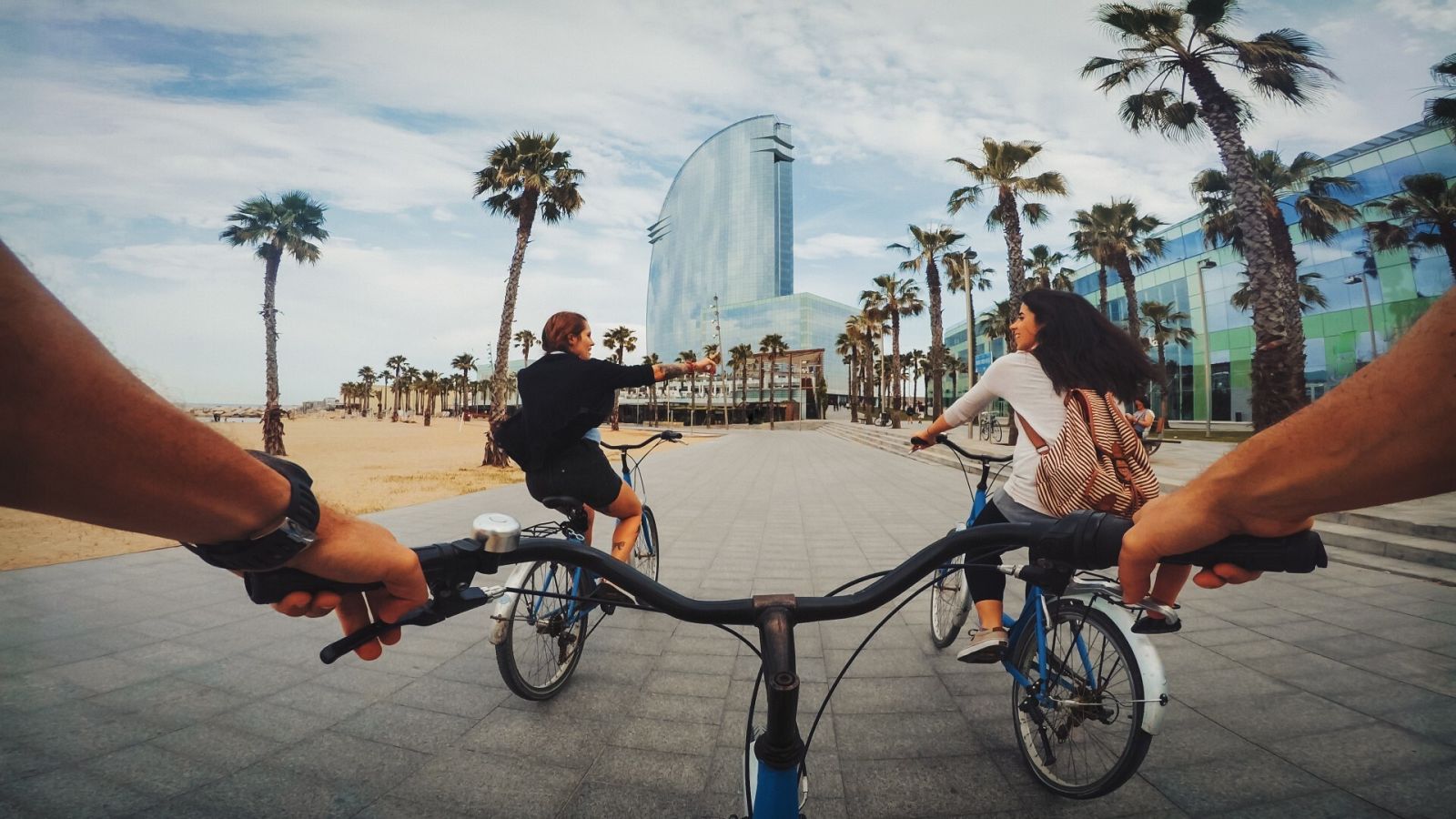 Tres ciclistas circulan por el paseo marítimo en la Barceloneta