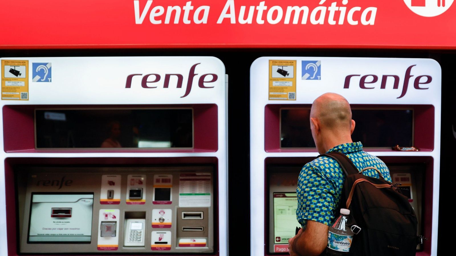 Viajeros gestionan la compra de sus abonos en máquinas expendedoras de billetes en una estación de Madrid