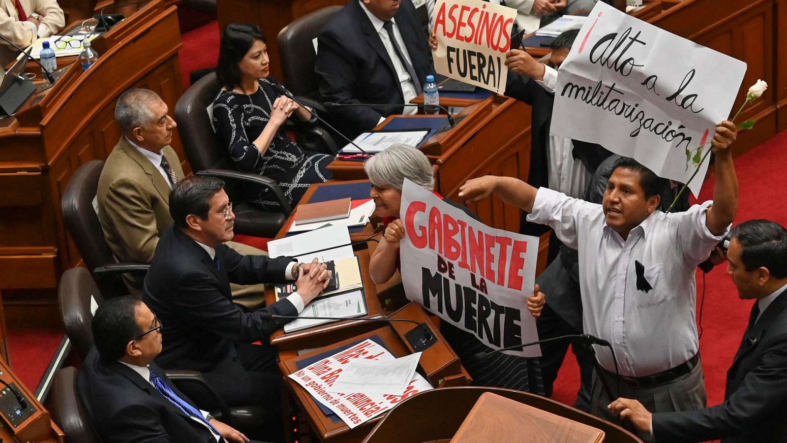 Miembros del Congreso sostienen pancartas mientras le gritan al primer ministro de Perú, Alberto Otarola, en Lima.