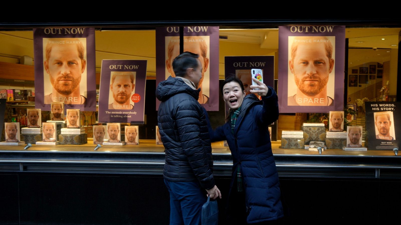 Una pareja se hace un 'selfie' en un escaparate repleto de ejemplares de 'Spare', en Londres
