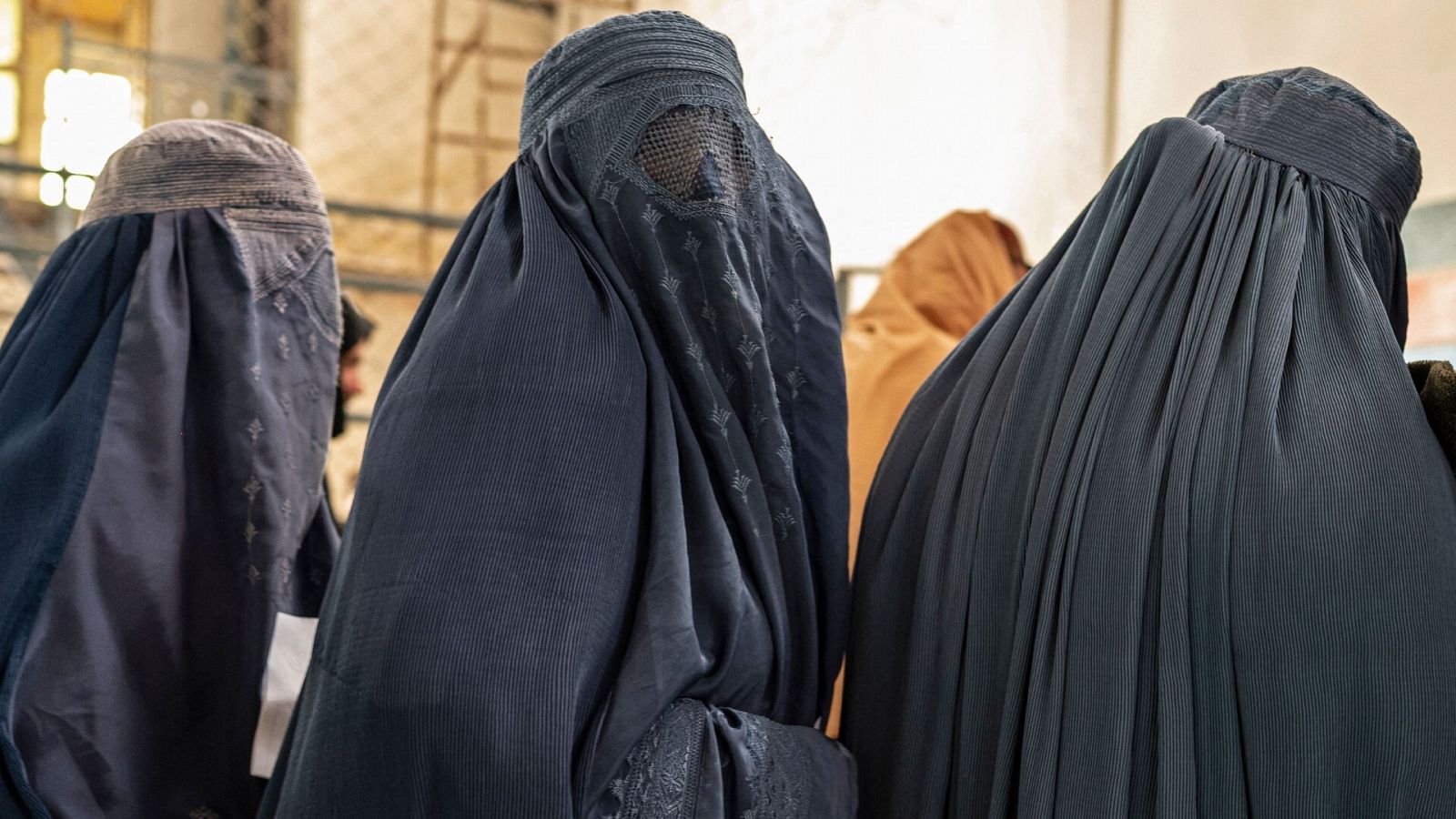 Mujeres afganas vestidas con burka hacen cola mientras esperan recibir ayuda alimentaria de una ONG en Kabul