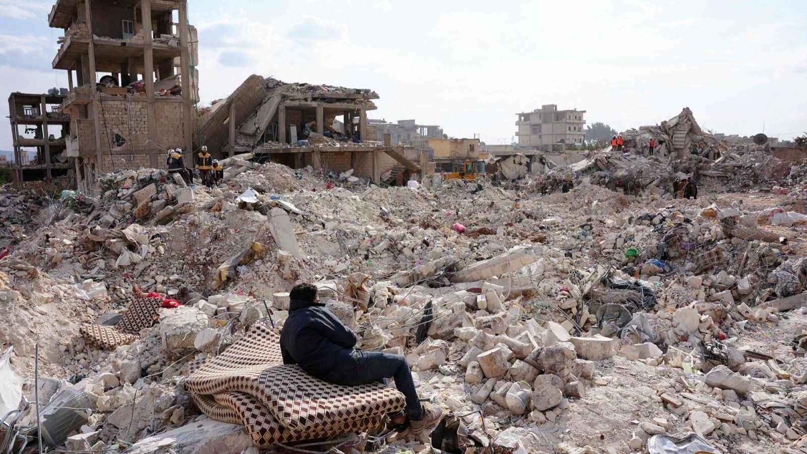 Un residente descansa sobre un colchón mientras continúan las operaciones de búsqueda en Siria